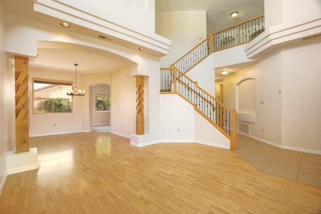 unfurnished living room with stairs, wood finished floors, visible vents, and baseboards