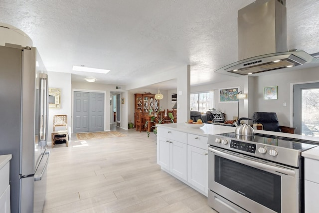 kitchen featuring stainless steel appliances, light wood-style flooring, open floor plan, white cabinets, and exhaust hood