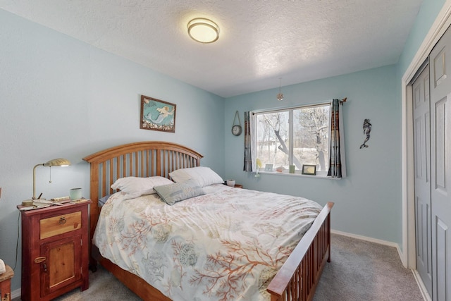 bedroom featuring a closet, light carpet, a textured ceiling, and baseboards