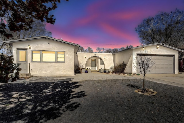 view of front facade with driveway, a garage, and stucco siding