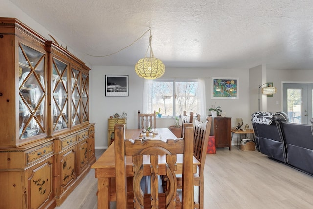 dining room with a textured ceiling and light wood-style flooring