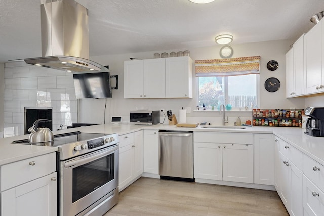 kitchen featuring white cabinets, island exhaust hood, stainless steel appliances, and a sink