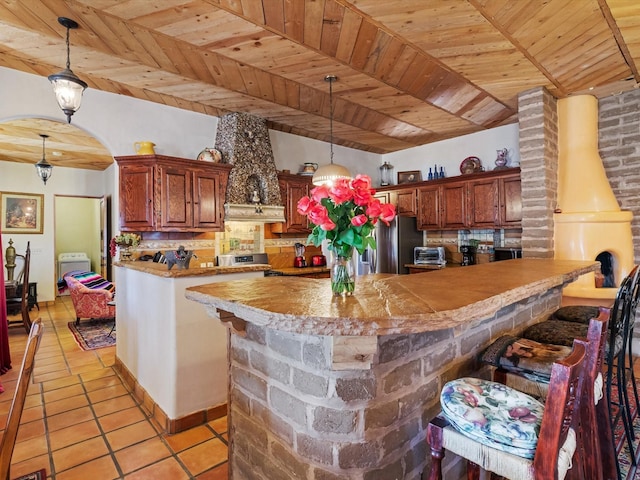 kitchen featuring light tile patterned floors, arched walkways, wood ceiling, a breakfast bar, and a peninsula