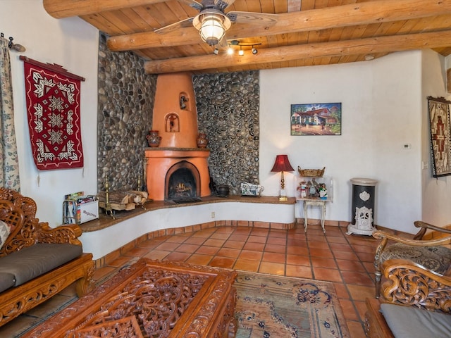 living room with a ceiling fan, wood ceiling, a large fireplace, tile patterned flooring, and beamed ceiling