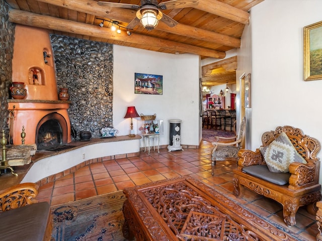 tiled living room featuring a warm lit fireplace, wooden ceiling, ceiling fan, and beam ceiling