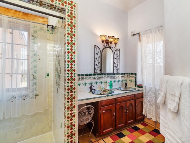 bathroom featuring tasteful backsplash, a tile shower, and vanity