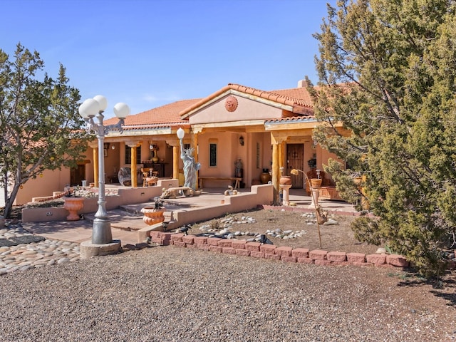 view of front of property featuring a patio, a tiled roof, and stucco siding