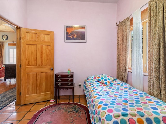 bedroom featuring arched walkways and light tile patterned flooring