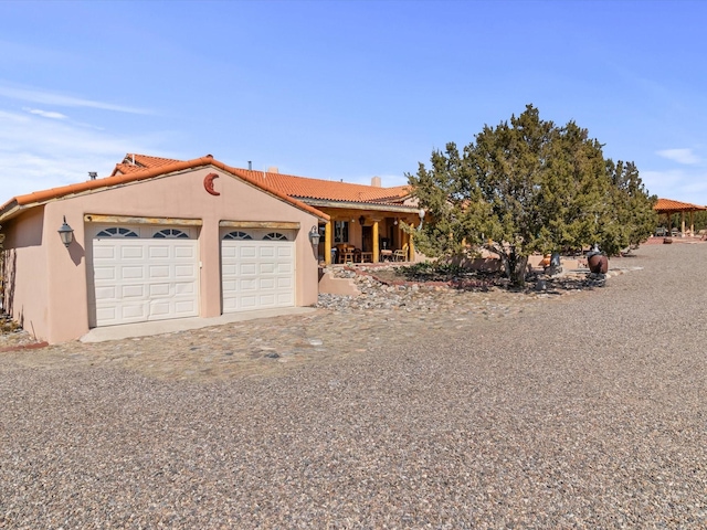 view of front facade featuring a garage, driveway, a tiled roof, and stucco siding