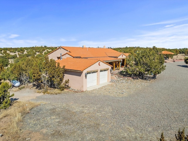 view of front of home with driveway, stucco siding, a garage, and a tiled roof