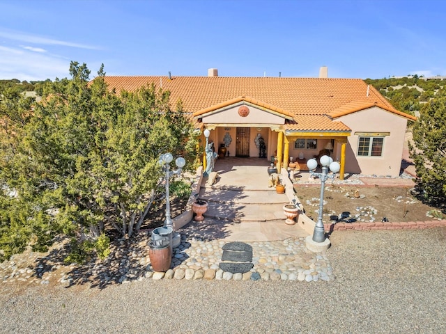 mediterranean / spanish-style home featuring a patio area, a tiled roof, and stucco siding