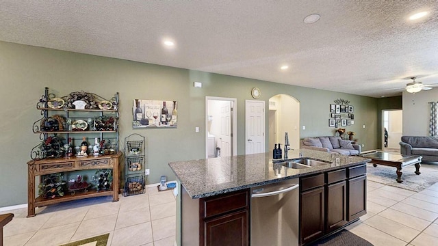 kitchen featuring dishwasher, light tile patterned floors, arched walkways, and a sink