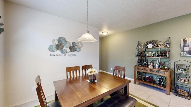 dining space featuring light tile patterned floors, baseboards, and a textured ceiling