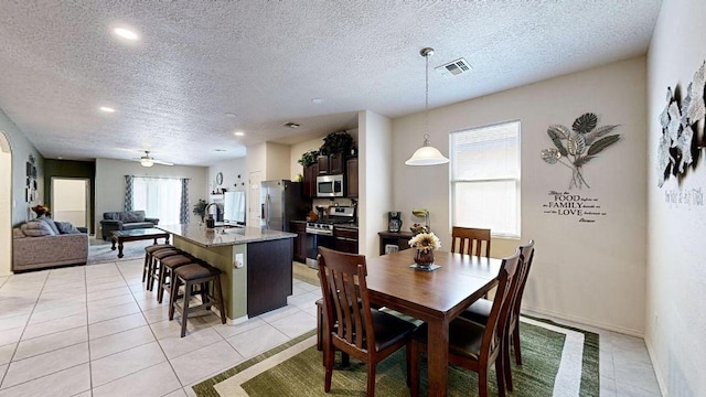 dining area featuring light tile patterned floors, a ceiling fan, visible vents, and a textured ceiling