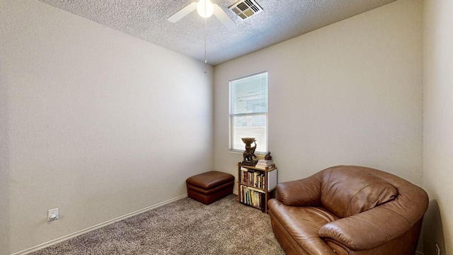 sitting room with carpet, visible vents, ceiling fan, and a textured ceiling