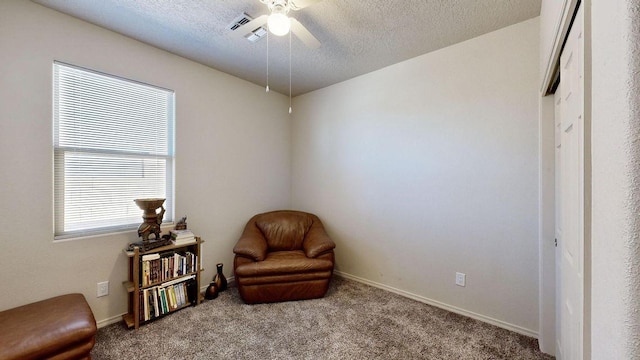 living area featuring carpet floors, visible vents, a textured ceiling, and baseboards