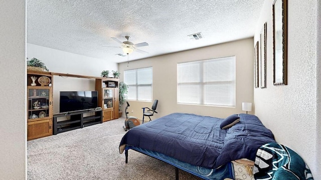 bedroom with carpet floors, visible vents, a textured wall, ceiling fan, and a textured ceiling