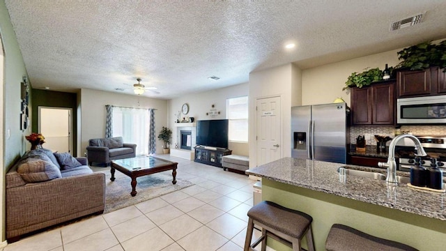 kitchen with visible vents, open floor plan, stainless steel appliances, dark brown cabinets, and a sink