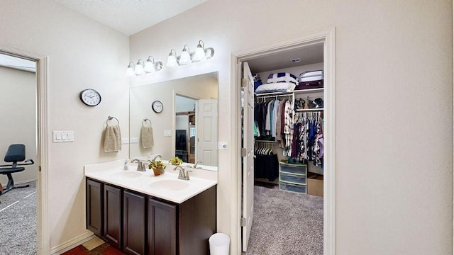 bathroom featuring double vanity, a spacious closet, and a sink