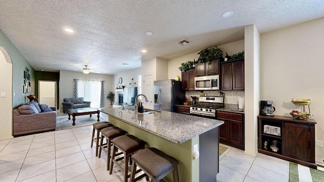 kitchen featuring light tile patterned floors, a breakfast bar, a sink, visible vents, and appliances with stainless steel finishes