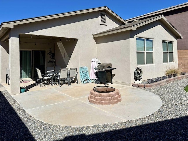 back of property featuring a patio area, a fire pit, outdoor dining area, and stucco siding