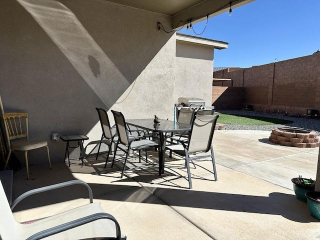 view of patio / terrace featuring outdoor dining space, a grill, fence, and a fire pit