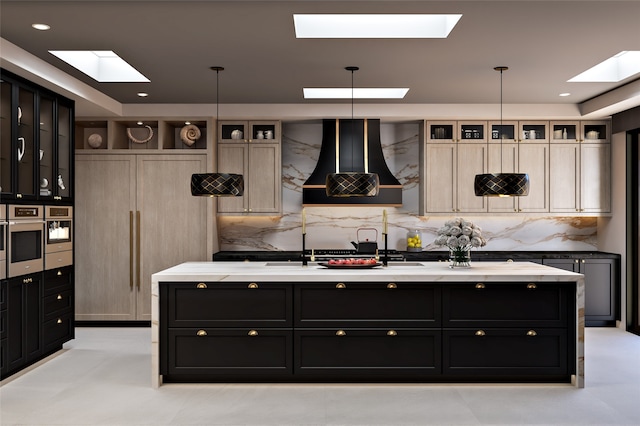 298 Brownell Howland, Santa Fe, NM 87501 - kitchen featuring a skylight, custom range hood, dark cabinetry, tasteful backsplash, and a kitchen island with sink