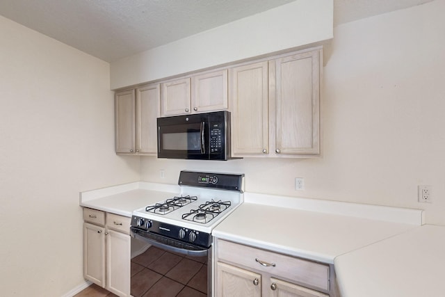 kitchen featuring black microwave, light countertops, light tile patterned floors, and gas range