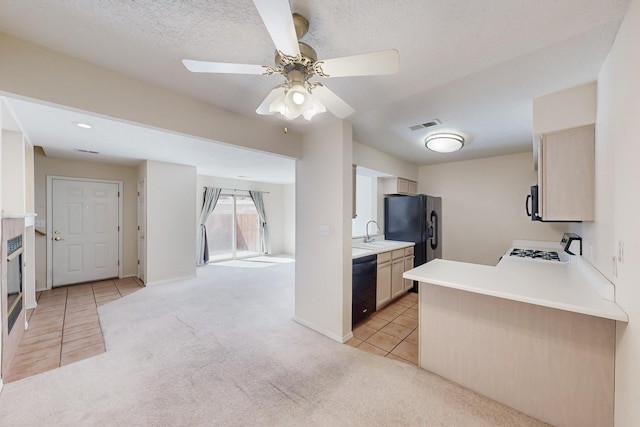 kitchen featuring light tile patterned floors, light colored carpet, visible vents, a sink, and black appliances