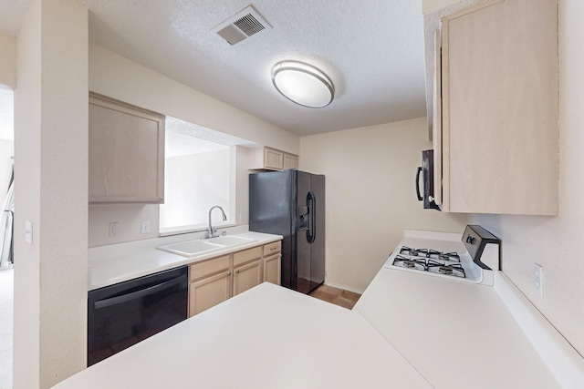 kitchen with visible vents, light countertops, light brown cabinetry, black appliances, and a sink