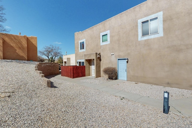 back of property with fence and stucco siding