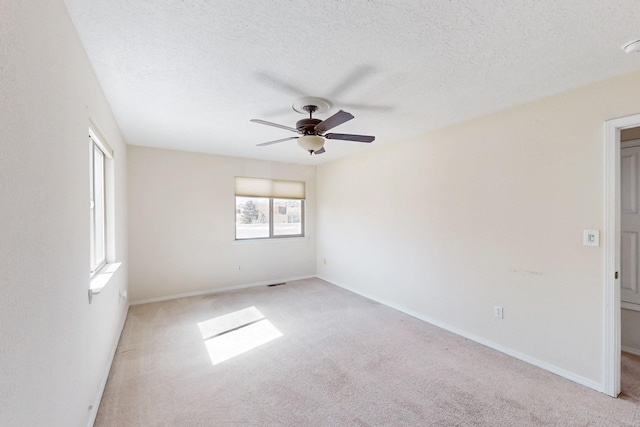 unfurnished room with ceiling fan, a textured ceiling, light carpet, visible vents, and baseboards