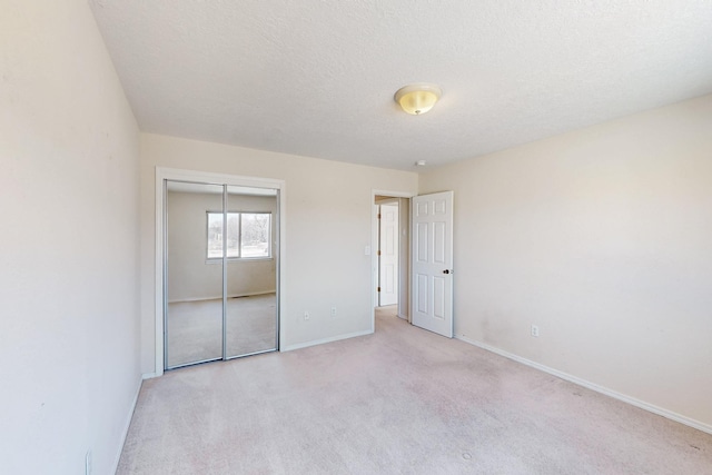 unfurnished bedroom with carpet floors, a closet, a textured ceiling, and baseboards