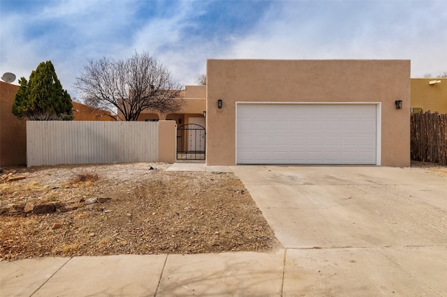 southwest-style home featuring driveway, a gate, fence, and stucco siding