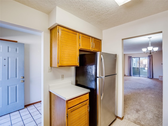 kitchen featuring light carpet, freestanding refrigerator, light countertops, a textured ceiling, and a chandelier