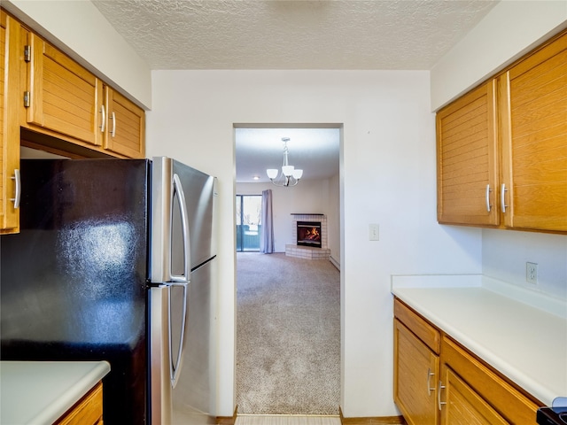 kitchen with light carpet, freestanding refrigerator, light countertops, a textured ceiling, and a brick fireplace