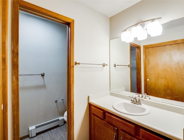 half bathroom featuring toilet, a baseboard heating unit, and vanity