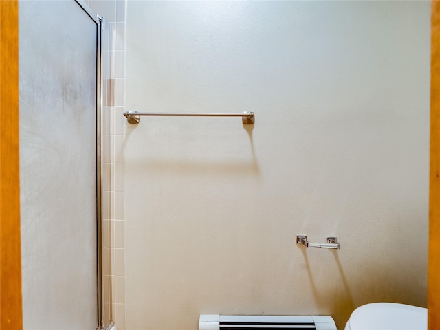 bathroom with a baseboard radiator, a shower with door, and toilet