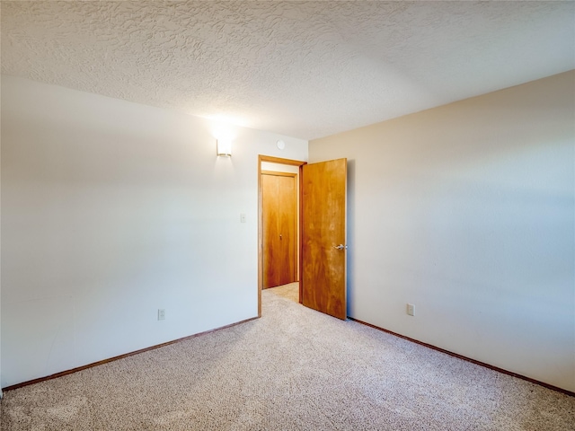 empty room featuring a textured ceiling, baseboards, and carpet flooring