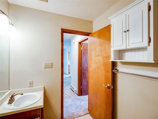 bathroom featuring a textured ceiling, baseboard heating, and vanity