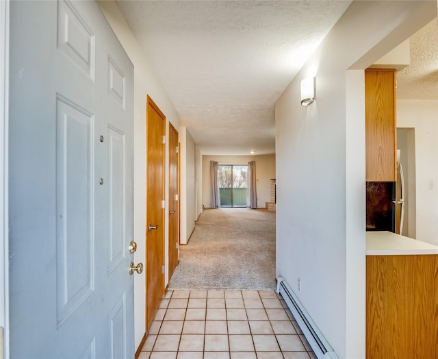 corridor featuring light tile patterned floors, baseboard heating, a textured ceiling, and light colored carpet