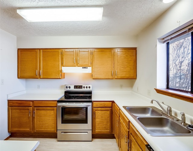 kitchen featuring light countertops, electric range, a sink, and under cabinet range hood