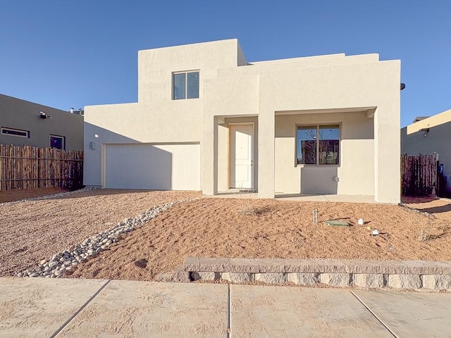 view of front facade featuring an attached garage, fence, and stucco siding