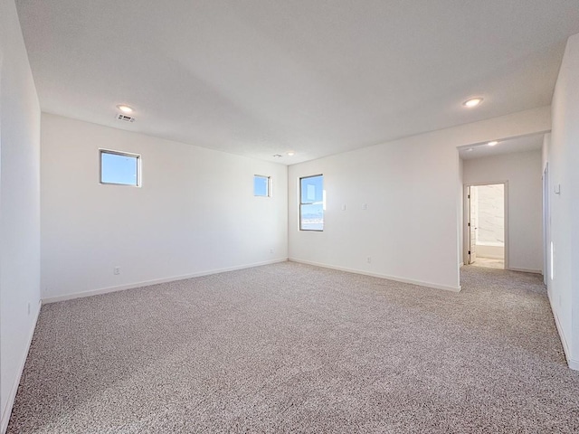 unfurnished room with light carpet, recessed lighting, visible vents, and baseboards