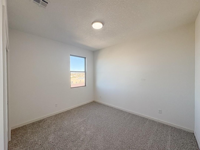 spare room featuring baseboards, a textured ceiling, visible vents, and carpet flooring