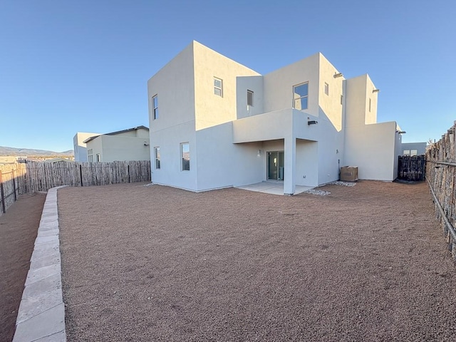 back of house with a fenced backyard, a patio, central AC, and stucco siding