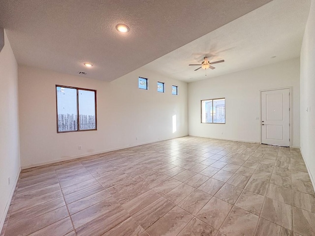 empty room with ceiling fan, baseboards, and a textured ceiling