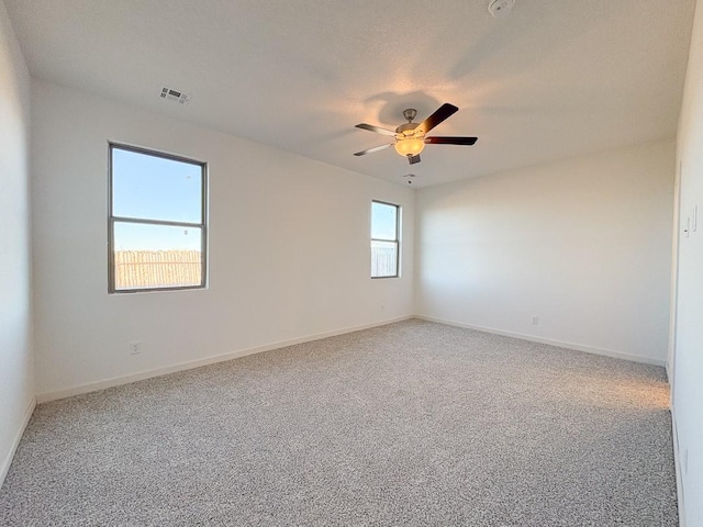 carpeted spare room with visible vents, ceiling fan, and baseboards