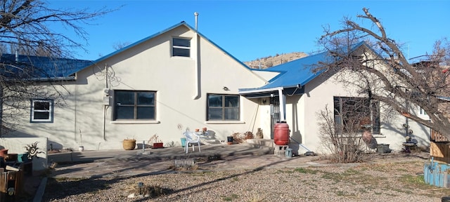 back of house featuring metal roof, a patio, and stucco siding