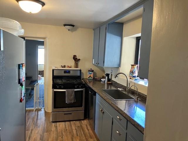 kitchen featuring dark wood-style flooring, a sink, gray cabinetry, stainless steel appliances, and dark countertops